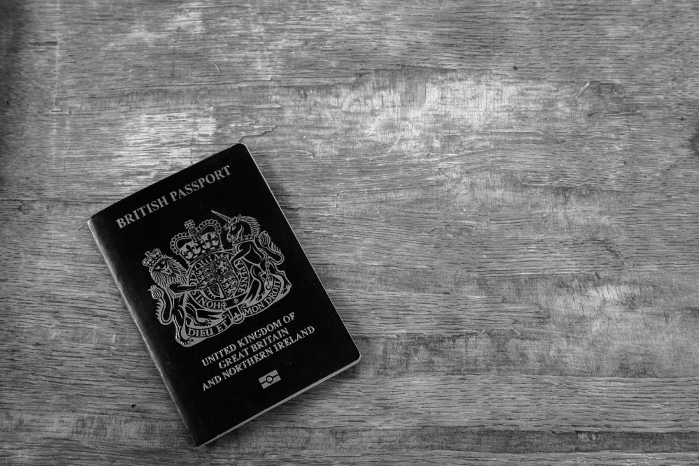 Grayscale Close Up Photo of British passport on wooden background