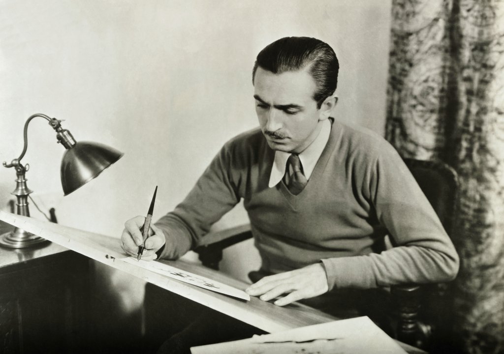 Grayscale Portrait Photo of Walt Disney working at his drawing board