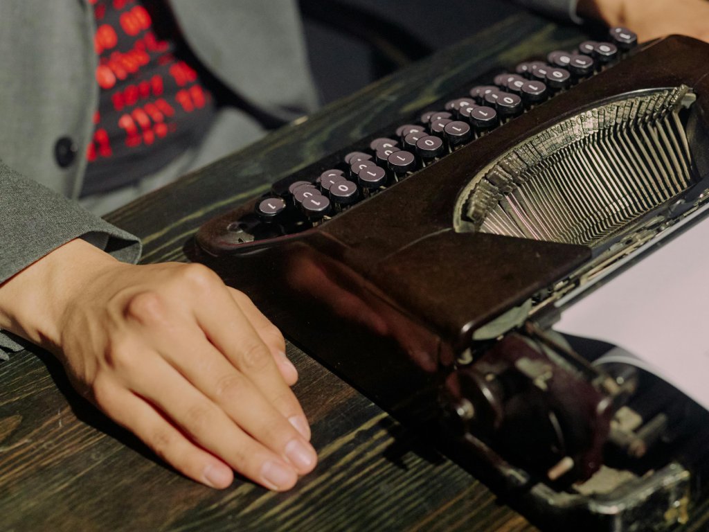 Photo of Person Sitting at Desk with Typewriter