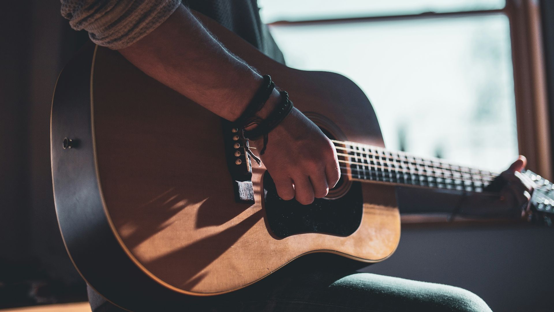 man playing acoustic guitar selective focus photography