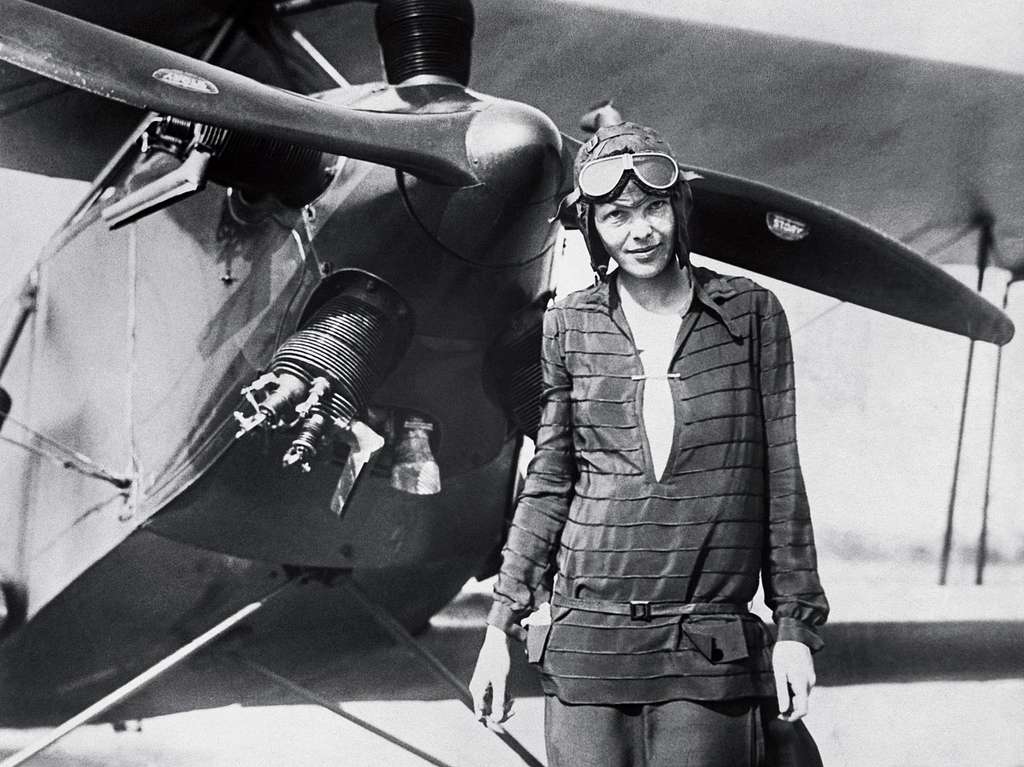 Amelia Earhart standing in front of an airplane