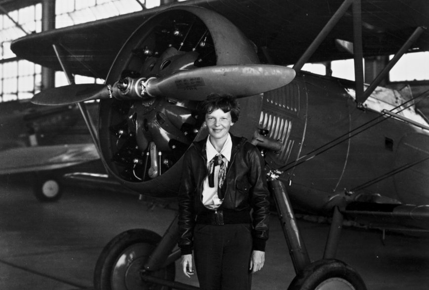 Amelia Earhart standing in front of an airplane