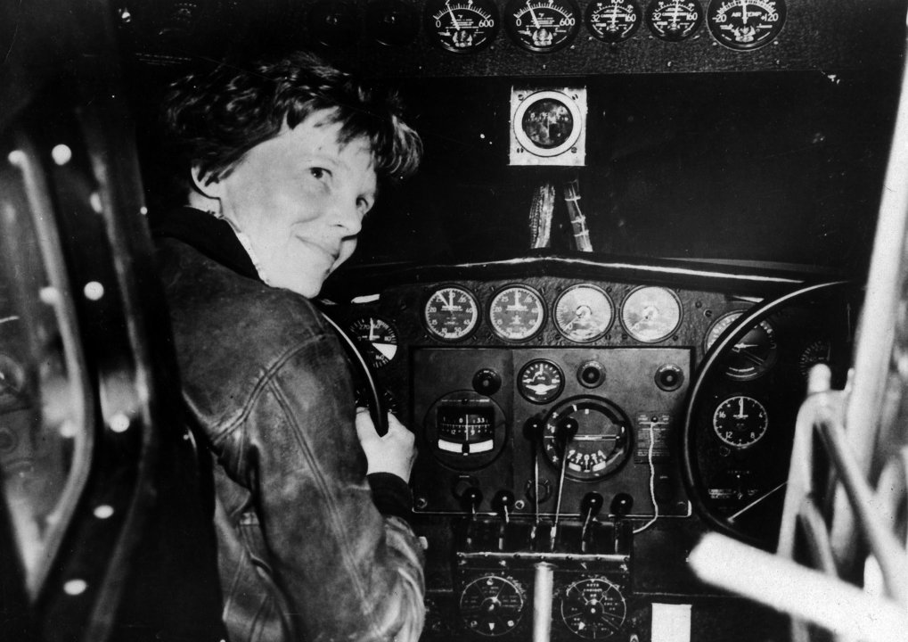 Photograph showing Amelia Earhart sitting in the cockpit of an airplane