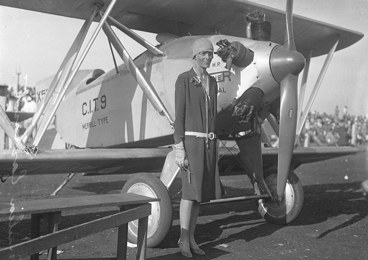 Amelia Earhart, standing beside a Merrill CIT-9 Safety Plane