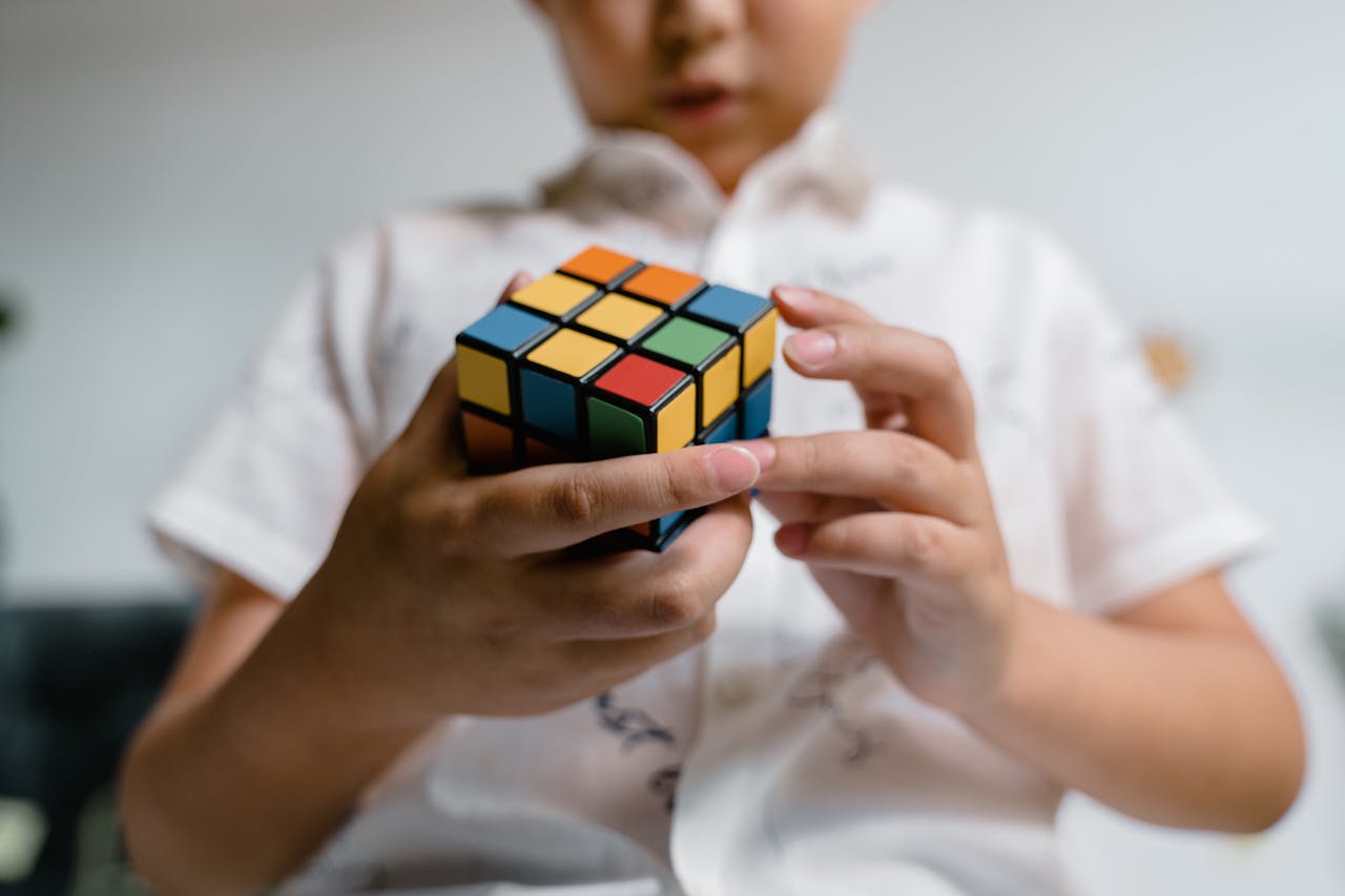 Close-Up Photo of a Child Solving a Rubik's Cube