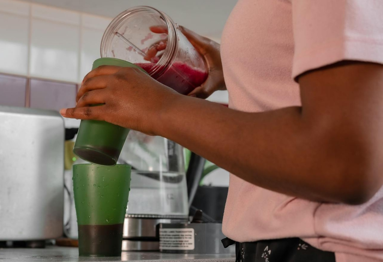 Woman Pouring Shake in Two Green Cups