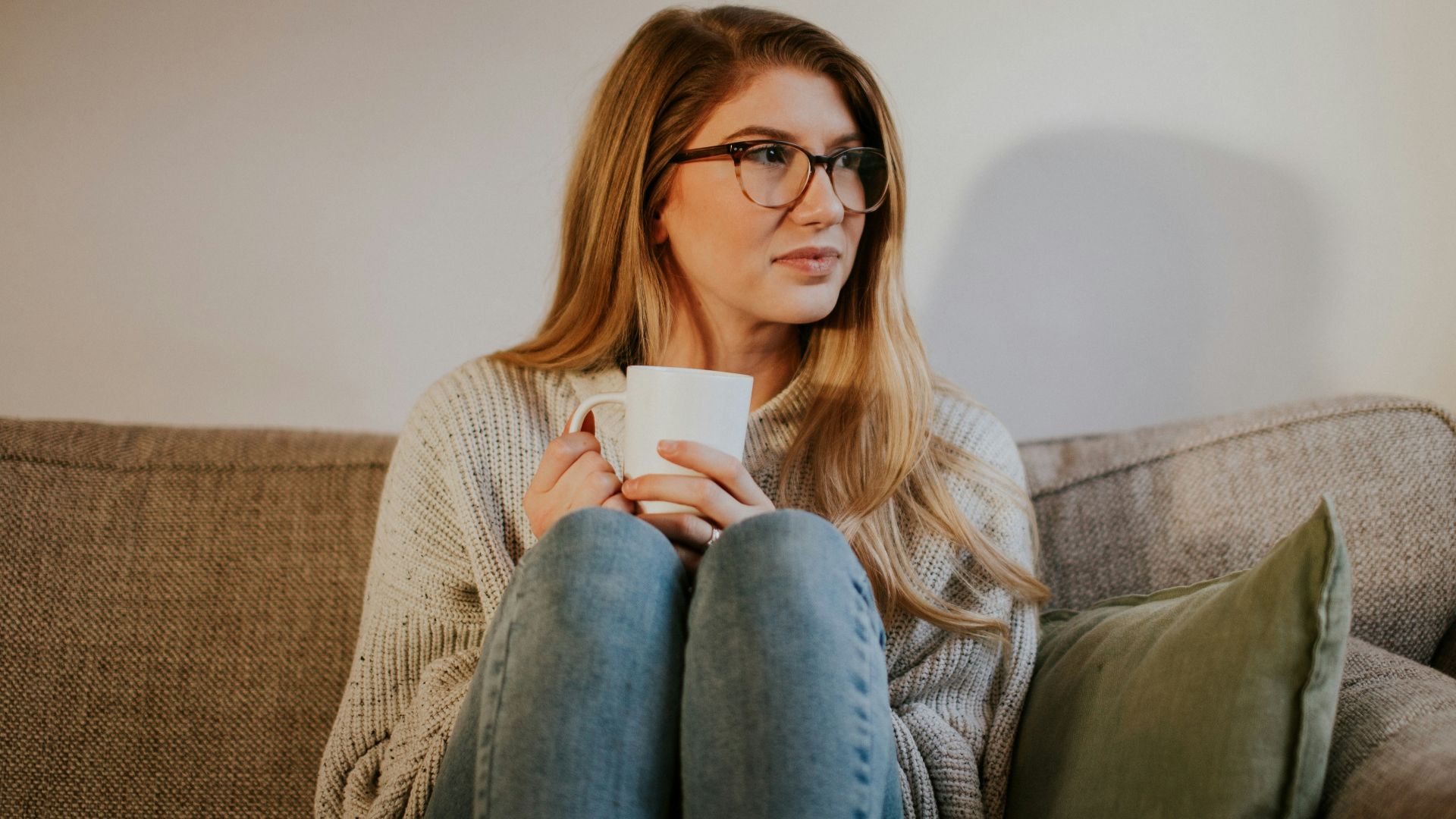 woman in blue denim jeans sitting on gray sofa