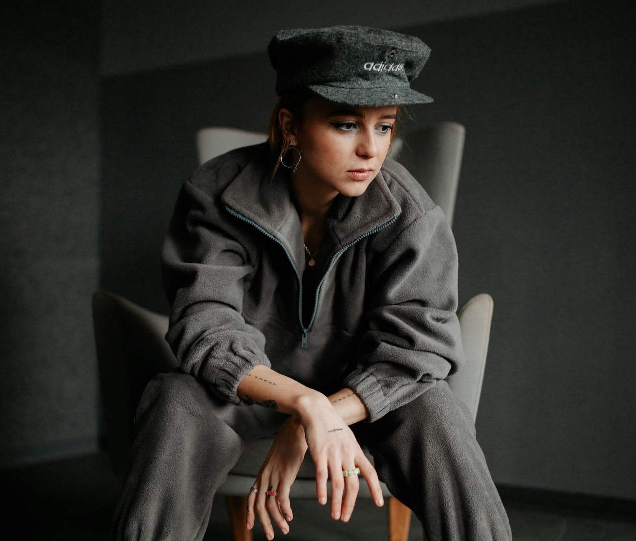 Woman Wearing a Khaki Fleece Tracksuit and a Hat Posing on an Armchair