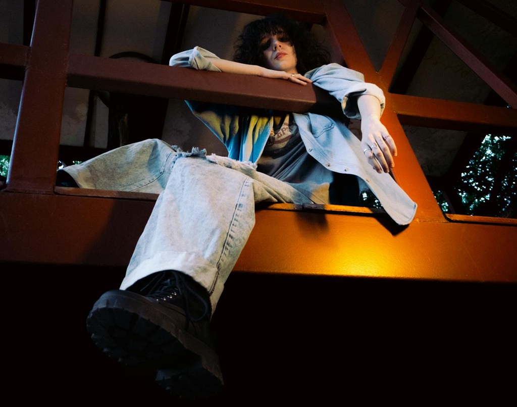 Pensive Young Adult Relaxing on Wooden Structure