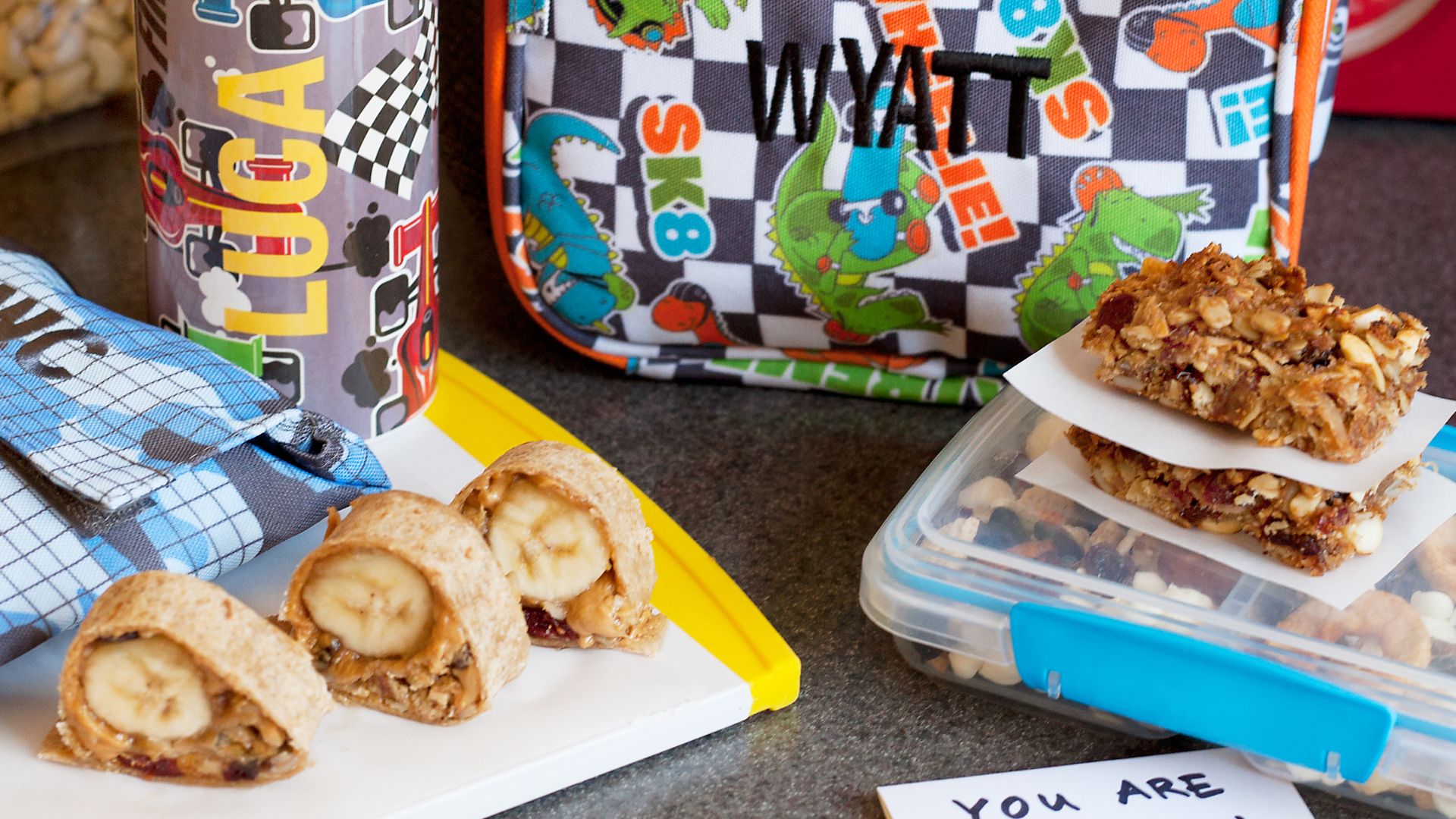 File:Peanut butter banana sushi, oatmeal squares and dried fruit and nut mix snacks for kids with water bottle and lunch pail (15257104546).jpg