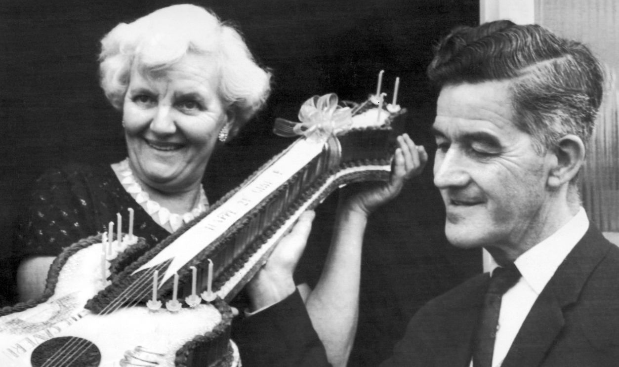 The Beatles 1964 Beatle fan, Jeanette Trust 16 from West Derby, Liverpool, presents Harold and Louise Harrison, parents of George Harrison, with a Birthday Cake in the shape of a Guitar, which she helped make, to celebrate his 21st Birthday. Pictured 25th February 1964. 
