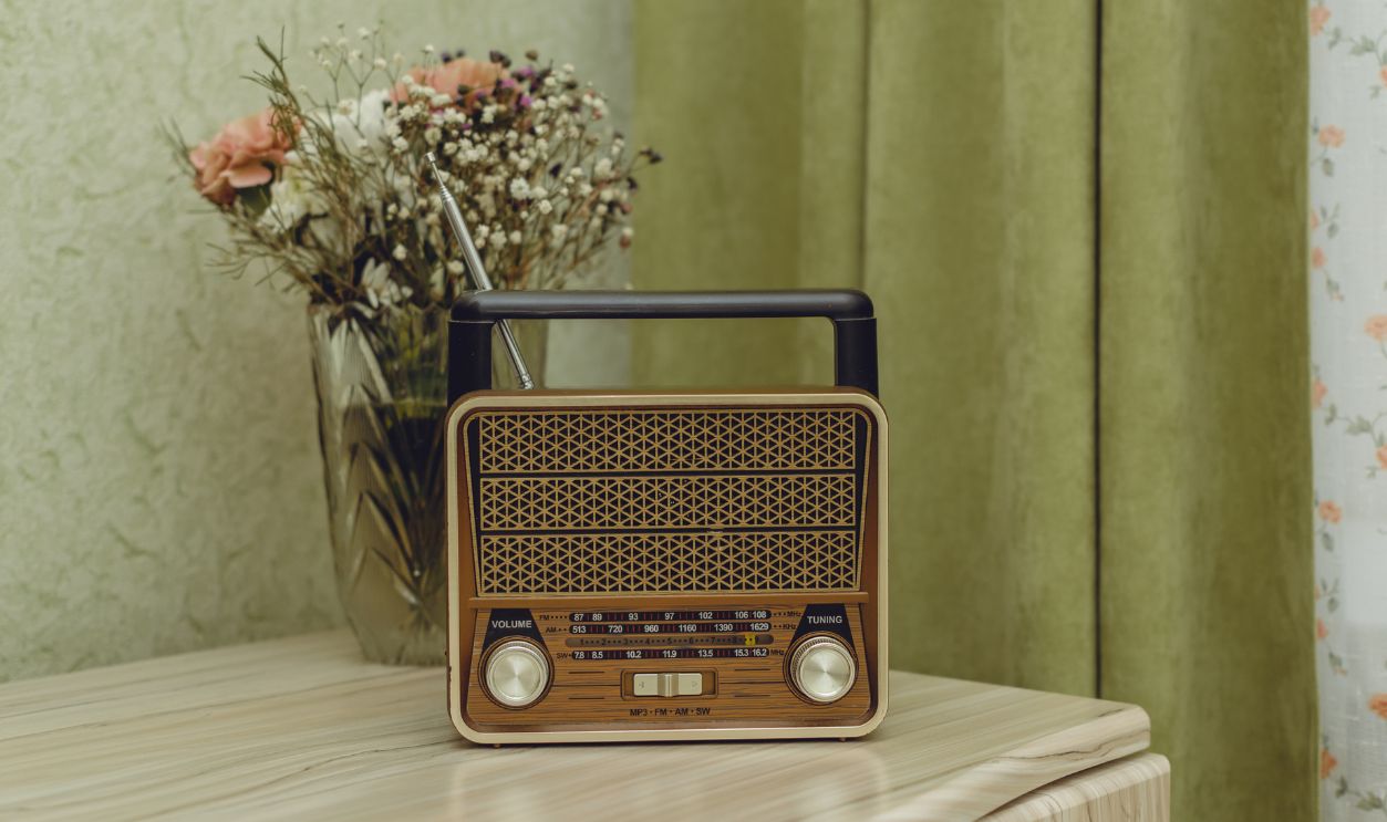 On a light wooden chest of drawers near the window with light green curtains