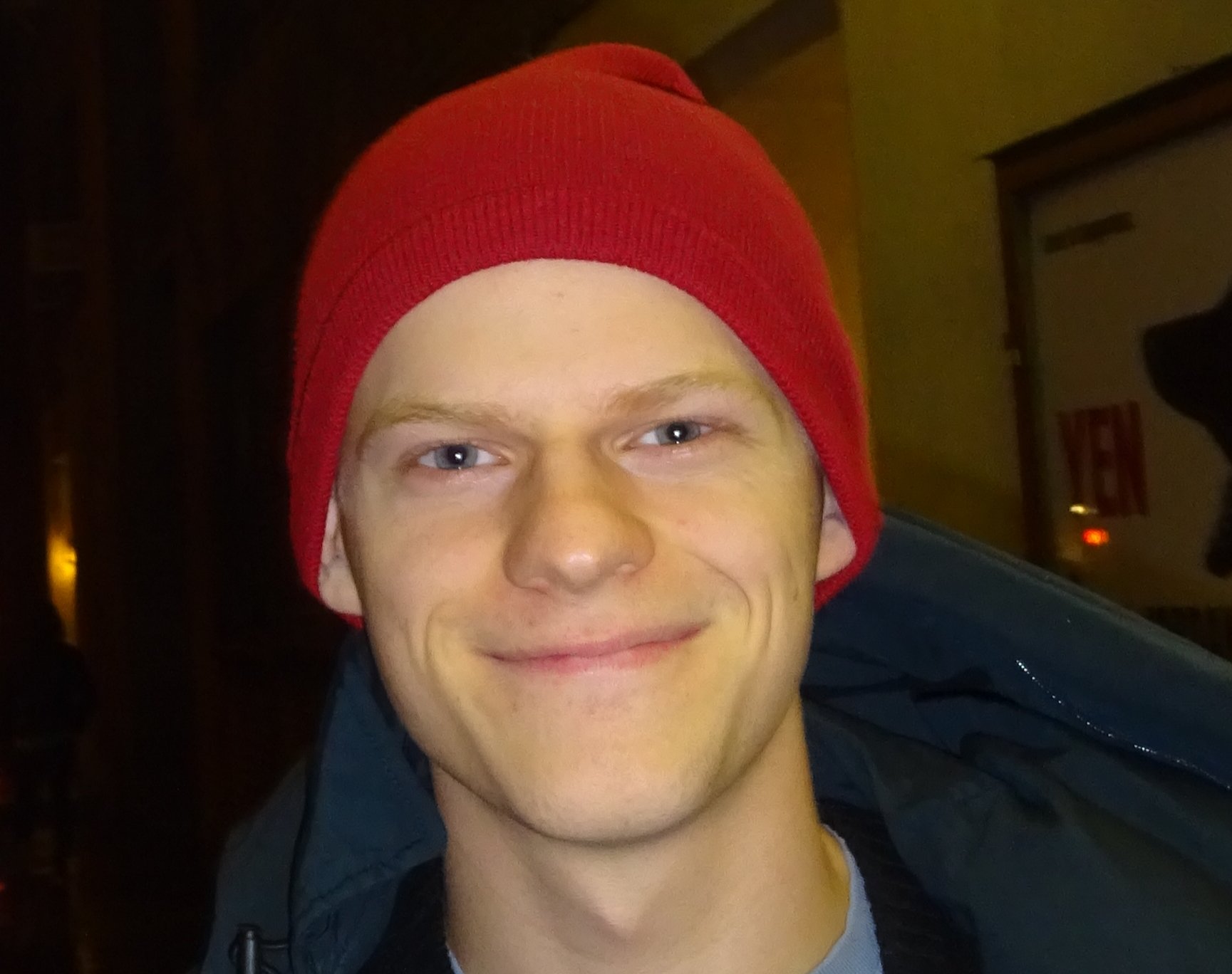 Portrait Photo of the American actor Lucas Hedges wearing red hat and smiling