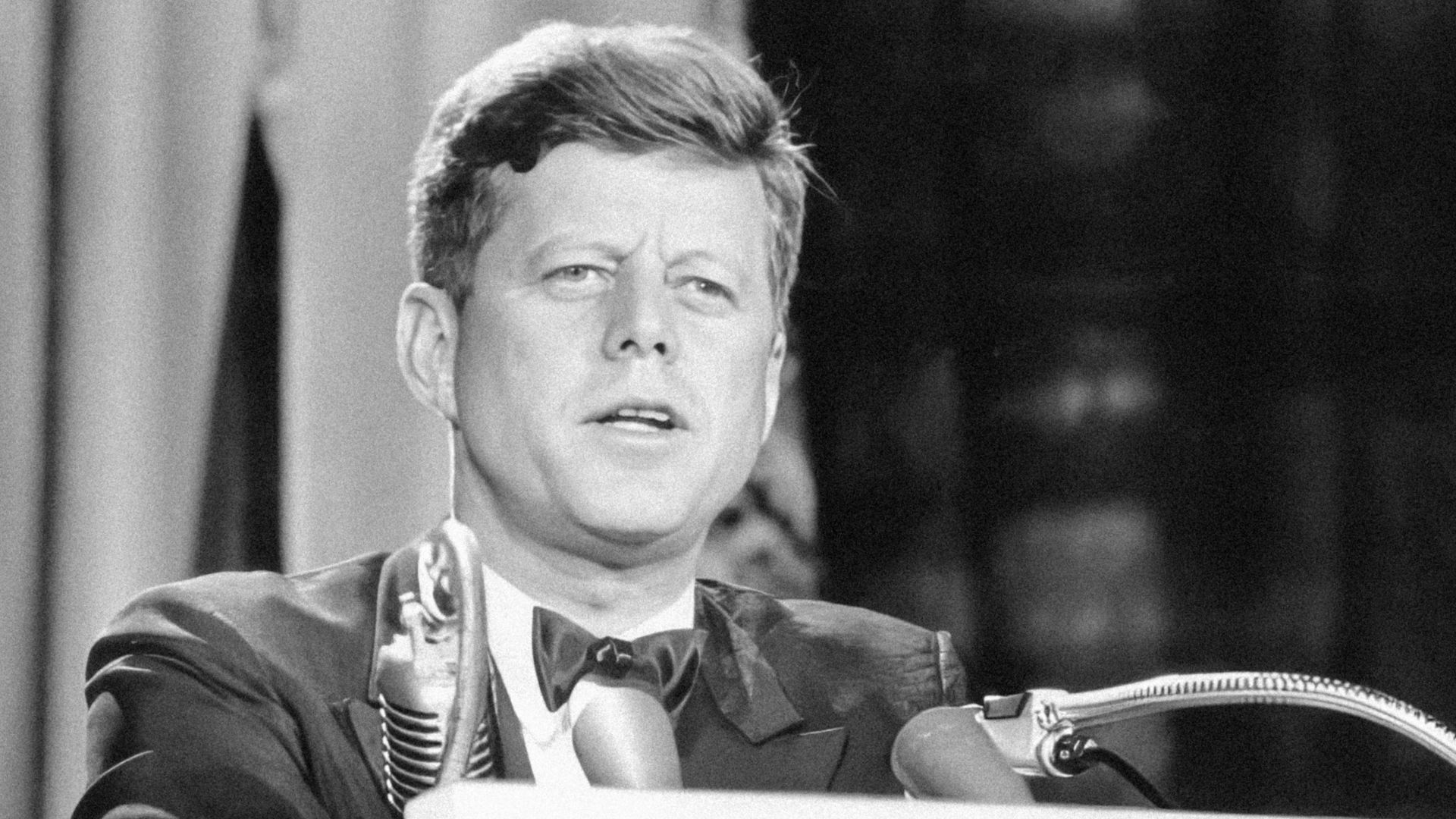 a man in a suit and tie standing at a podium
