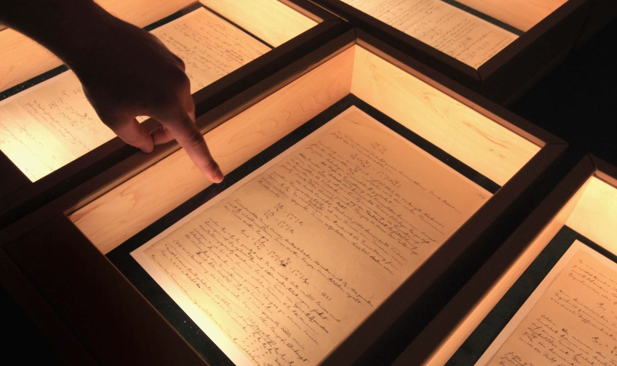 JERUSALEM - MARCH 09: In an almost pitch-dark room, an Israeli student inspects Albert Einstein's General Theory of Relativity on display in its entirety for the first time, at the Israeli Academy of Sciences and Humanities on March 9, 2010 in Jerusalem, Israel. Einstein donated the complete original forty-six page handwritten manuscript of his ground-breaking theory to The Hebrew University of Jerusalem during its inauguration in 1925. 