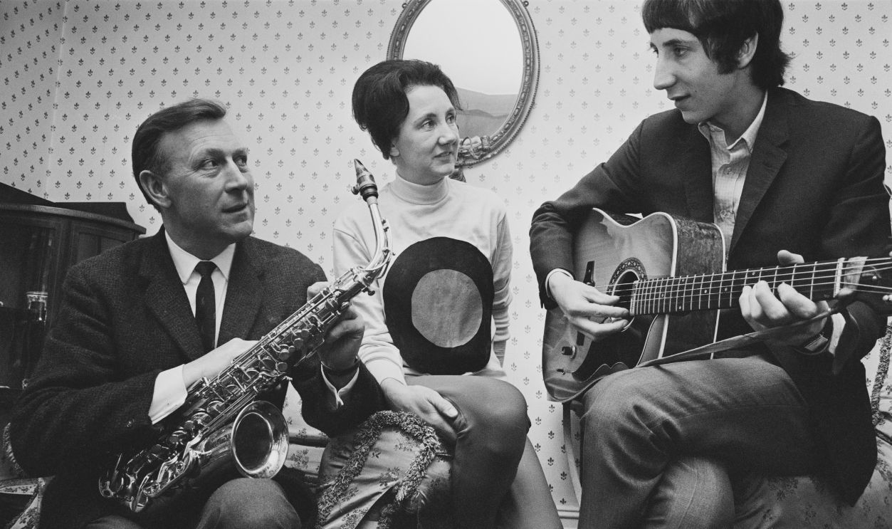 Gettyimages - 988346524, Pete Townshend And Parents Pete Townshend of The Who pictured playing an acoustic guitar with his father Cliff Townshend (1916-1986), saxophone player with the Squadronaires, and mother Betty at home in London on 30th March 1966. 