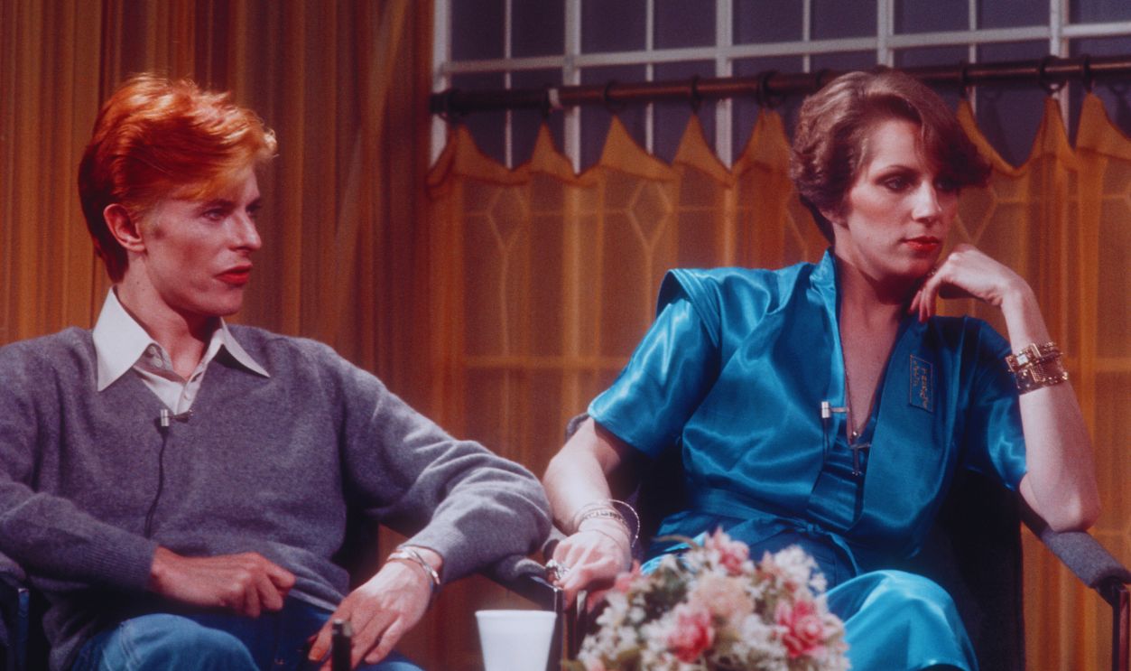Gettyimages - 176973693, Bowie On 'Good Morning America' LOS ANGELES, CA - FEBRUARY 1976: David Bowie and his wife Angela Bowie are interviewed on 'Good Morning America' by Rona Barrett in February, 1976 in Los Angeles, California.