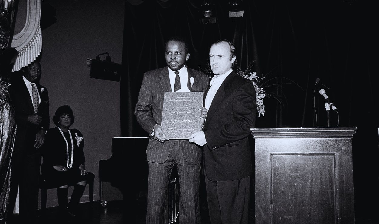 Getty Images - 1313936905, Rhythm And Blues Foundation Presents 1990 1991 Pioneer Awards NEW YORK - FEBRUARY 1991: Musician Phil Collins (Philip David Charles Collins LVO) poses for photos with Todd Mayfield, son of Curtis Mayfield during the 1990 1991 R&B Foundation Pioneer Awards at Tatou in New York, New York in November 1991.