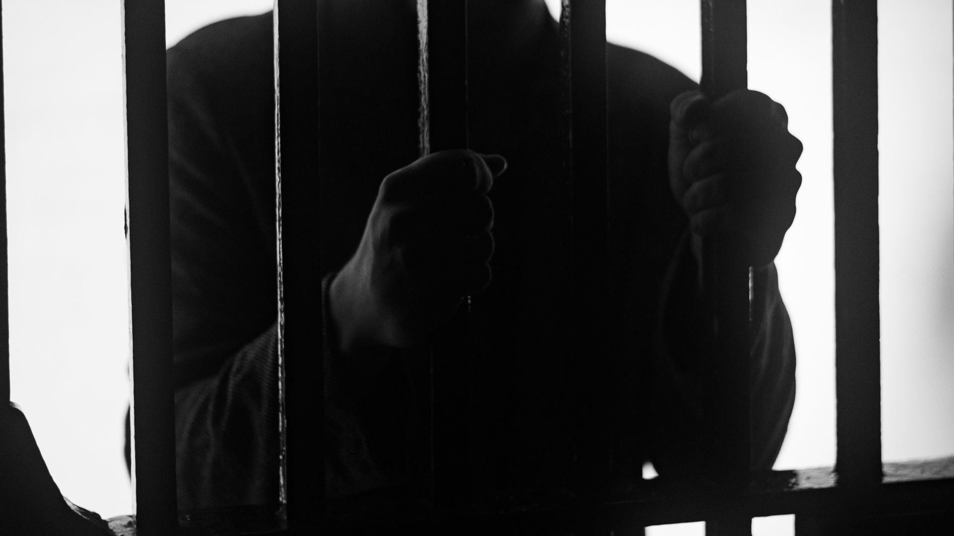 a man standing behind bars in a jail cell