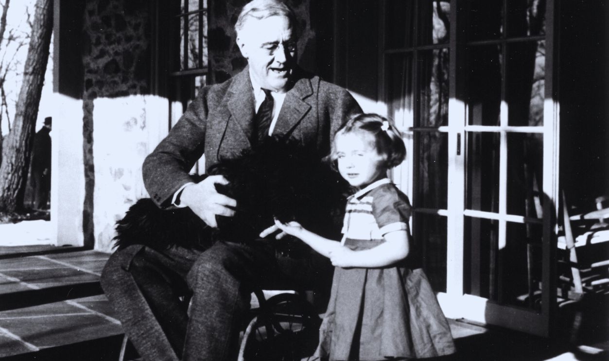 Gettyimages - 137822922, FDR On The Porch American President Franklin D. Roosevelt (1882 - 1945) poses with his dog Fala and a young girl named Ruthie Bie (later Ruth Bautista) on the porch at Top Cottage, Hyde Park, New York, February 1941. Bie was the granddaughter of the property caretaker, and the photo is one of only two that show Roosevelt in his wheelchair. 