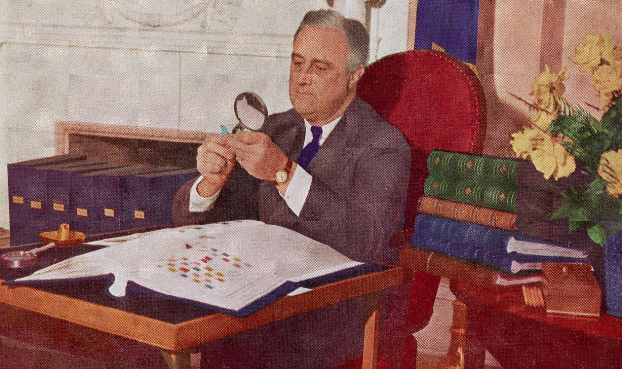 Gettyimages - 51332451, Franklin Delano Roosevelt US President Franklin Delano Roosevelt (1882 - 1945) holds a stamp under a magnifying glass while seated at his desk with his stamp collection, Washington, DC, circa 1944.