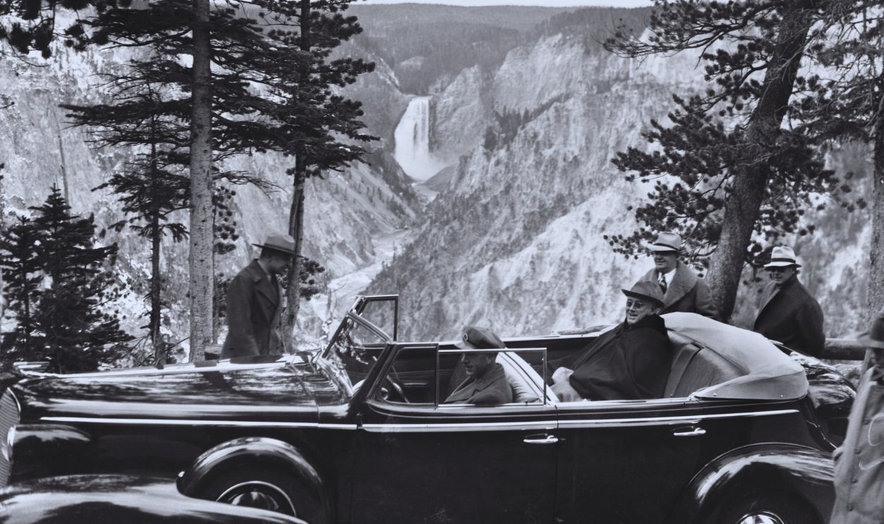 Gettyimages - 515169084, President Roosevelt Driving Through Yellowstone National Park (Original Caption) Backgrounded by a beautiful vista of Yellowstone National Park, President Franklin D. Roosevelt is pictured well muffled up against the chill air as he drove through here on his Western trip. The coolness of the air was well counter-balanced by the warmth of Wyoming's welcome to the Chief Executive.