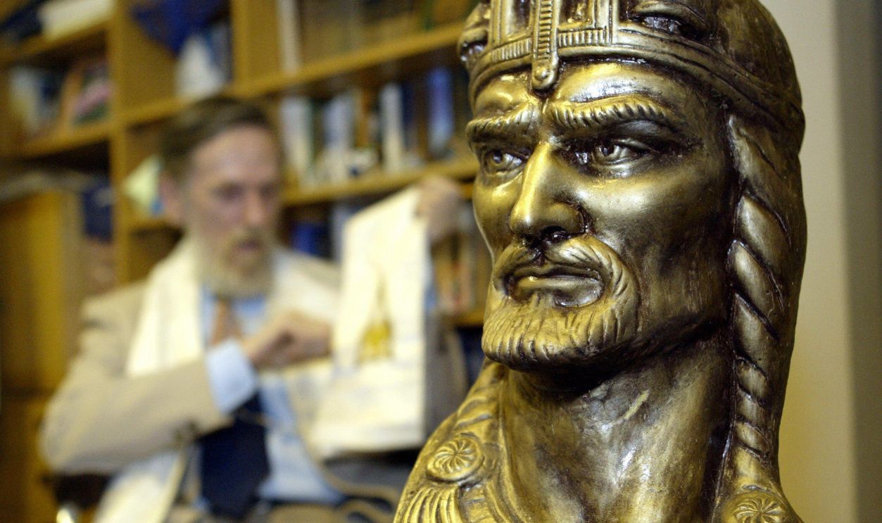 BUDAPEST, HUNGARY: Gyoergy Kisfaludy, leader of the Hungarian Hun minority and hierarch of their community 'Church of Universum' sits beside a bust of Attila the Hun at their headquarters in Budapest, 23 March 2005. More than 1,500 years after Attila the Hun plundered much of Europe, people claiming to be his descendants are campaigning to be recognized as an official minority in the newly joined European Union member-state Hungary. AFP PHOTO ATTILA KISBENEDEK
