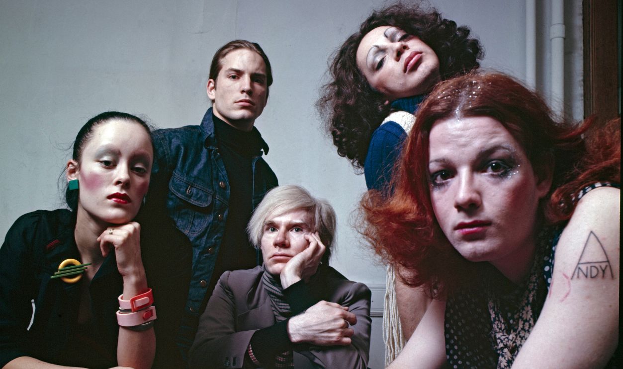 Andy Warhol photographed at the Factory with superstars Jane Forth, Jackie Curtis, Joe Dallesandro, and Holly Woodlawn. 