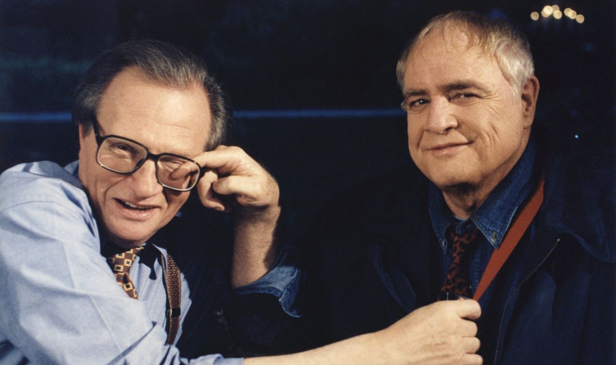 Actor Marlon Brando plants one on talk show host Larry King during the taping of 