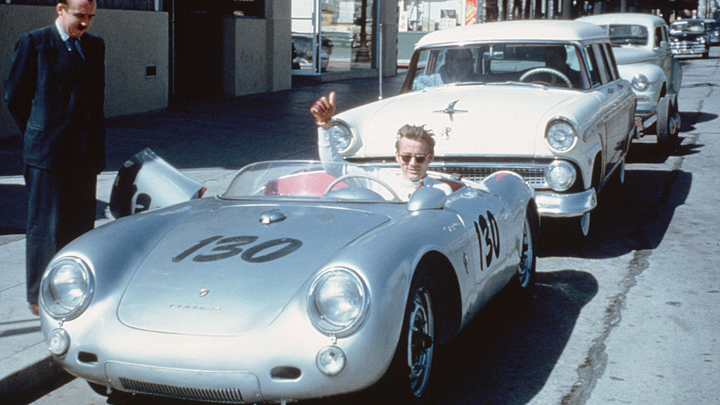Actor James Dean gives a thumbs-up sign from his Porsche 550 Spyder, the Little Bastard, while parked on Vine Street in Hollywood. Dean, who had taken up racing the year before, owned the car only nine days when he lost his life in a fatal highway accident while driving the Porsche to a Salinas race.