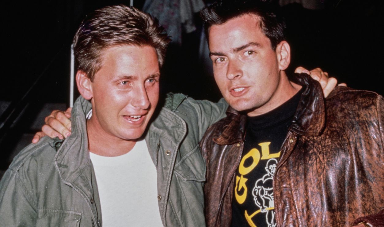 American actors Emilio Estevez, wearing a green M65 field jacket, with his brother Charlie Sheen, wearing a Type A-2 leather flight jacket and Gold's Gym t-shirt, at the premiere of John Badham's 'Stakeout', 1987.