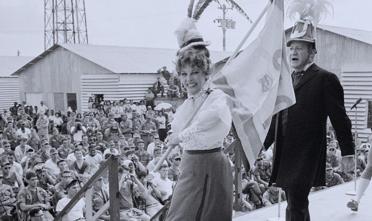 Gettyimages - 515036564, Martha Raye Performing for American Soldiers (Original Caption) Star Performance. Saigon, South Vietnam: Actress Martha Raye performs in Hello Dolly before 300 American soldiers at Camp Davis here. While belting out the final number of the show, she fainted in the 90 degree heat and was carried of the stage. She quickly recovered and said there would be no interruption in her performances.