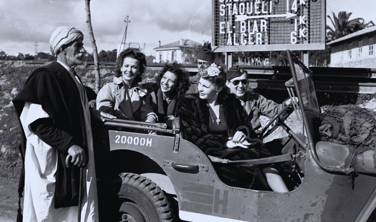 Gettyimages - 615315636, Celebrities in an Army Jeep Martha Raye, Caroll Landis, and Kay Francis ask a local Algerian for directions as they drive toward Algiers. | Location: West of Algiers, Algeria