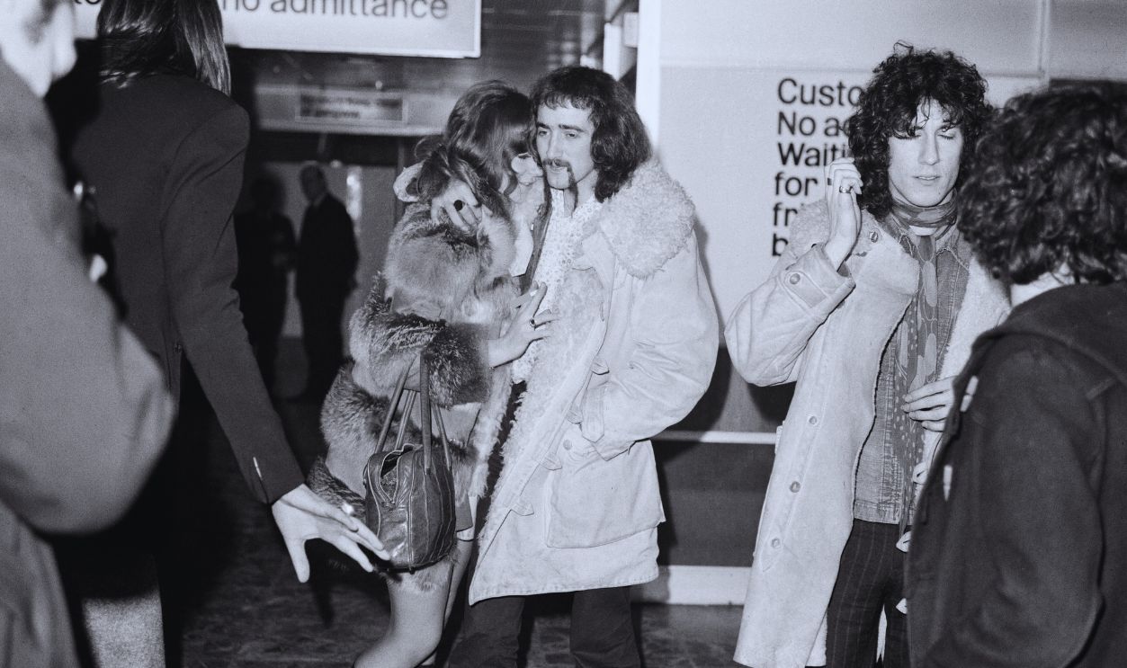 Gettyimages - 2164342428, Fleetwood Mac At Heathrow Airport 1969 John McVie of the group gives his wife a hug. 14th February 1969. Pop group Fleetwood Mac arrive at Heathrow Airport in London from the United States