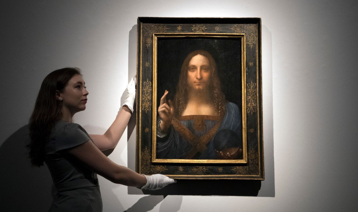 A member of staff poses with a painting by Leonardo da Vinci entitled 'Salvator Mundi' before it is auctioned in New York on November 15, at Christies on October 24, 2017 in London, England. The painting is the last Da Vinci in private hands and is expected to fetch around 100,000,000 USD.