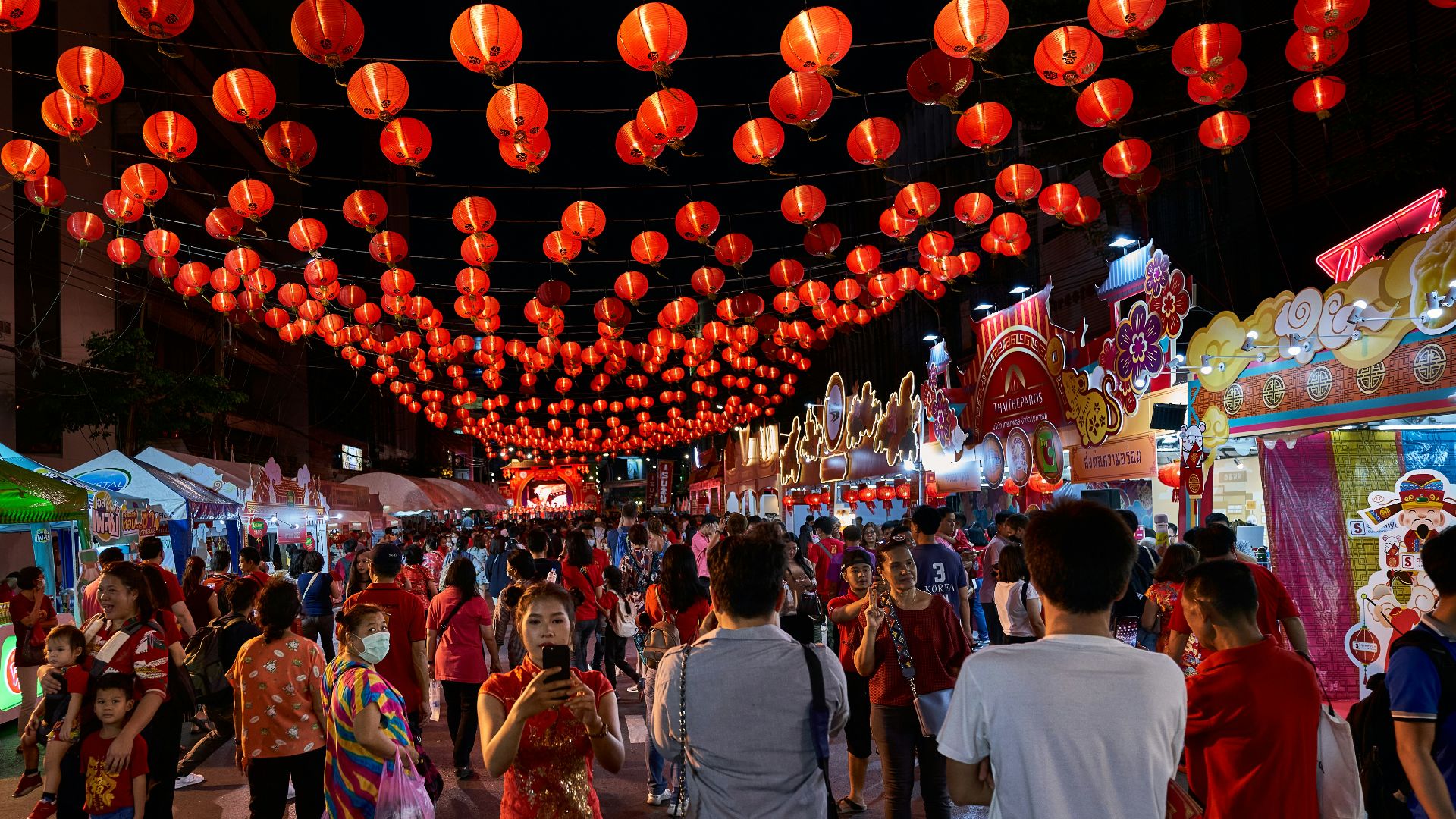 a crowd of people walking down a street under red lanterns