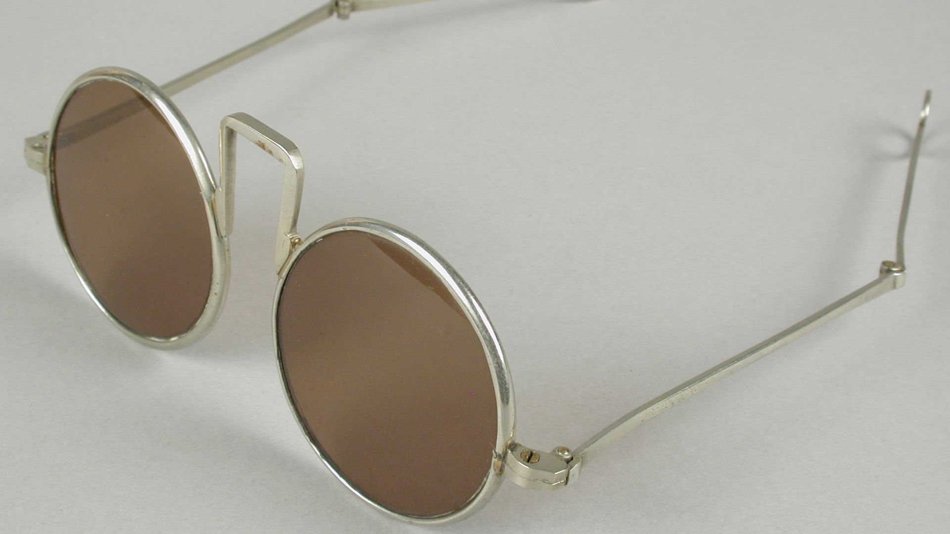 File:Mandarijnenbril, bril met ronde bruin getinte glazen op sterkte, zilverkleurig metalen montuur, rechthoekige brug en uitklapbare veren, objectnr 71130-1.JPG