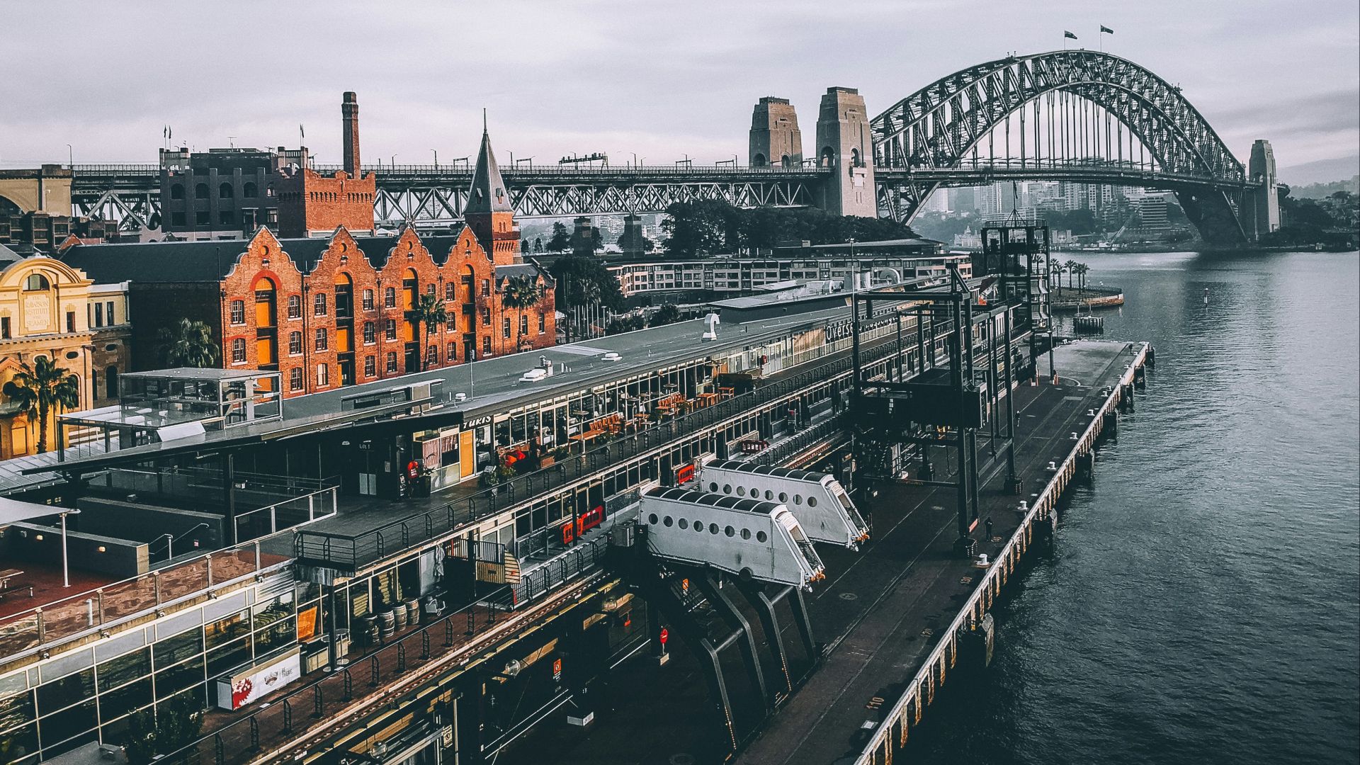 aerial photography of concrete buildings and bridge beside ocean under cloudy sky
