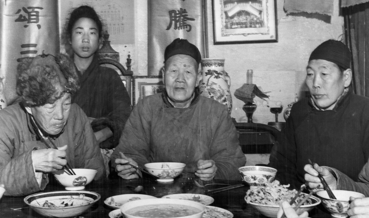 Chinese eunuchs sit at a dinner table to eat noodles.