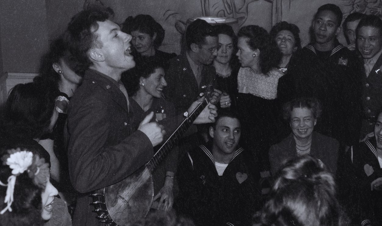 Gettyimages - 666092286, Pete Seeger Performs At Federal Labor Canteen American folk musician Pete Seeger (1919 - 2014) (standing left) plays banjo as he performs for US First Lady Eleanor Roosevelt (1884 - 1962) (seated, center) and others at the opening of the Federal Labor Canteen, Washington DC, February, 1944.