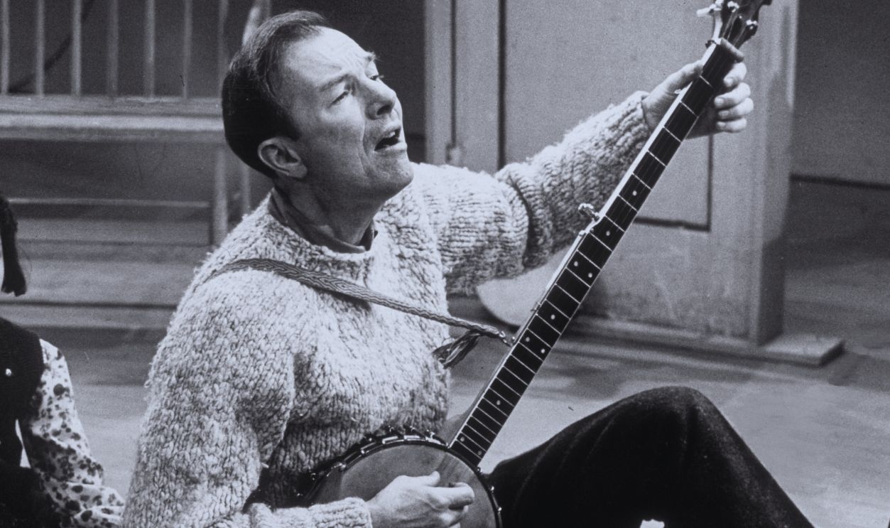 Gettyimages - 3202449, An Old Folkie 9th December 1965: American folk singer Pete Seeger, seated on the floor, performs a song on the banjo at the Mosque Theater in Newark, New Jersey.