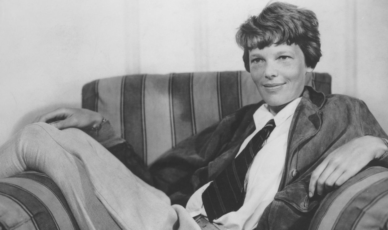 Amelia Earhart (1897-1937), American aviator, wearing a shirt and tie while reclining in an armchair, circa 1935.