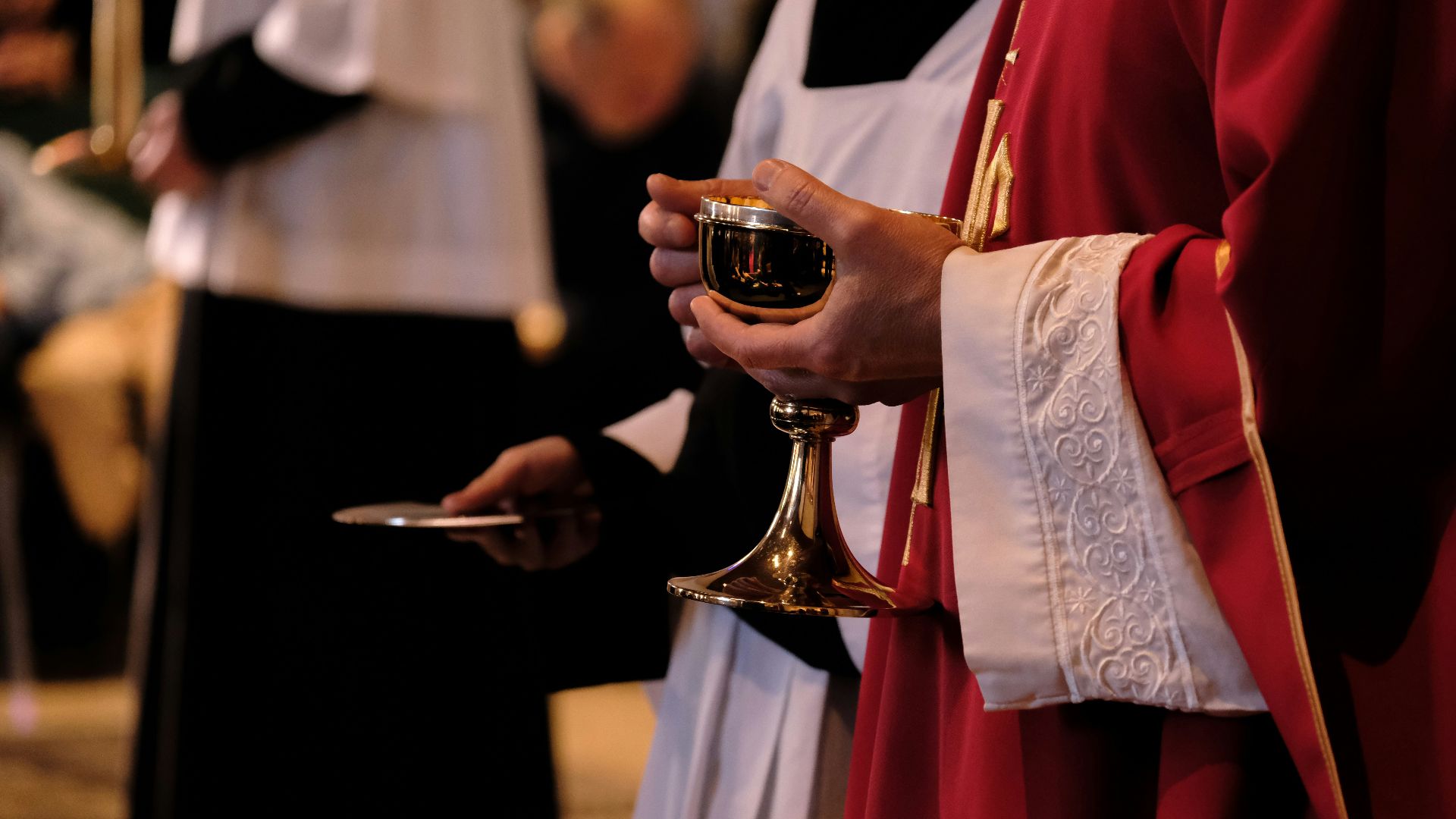 A priest is holding a chalice in a church