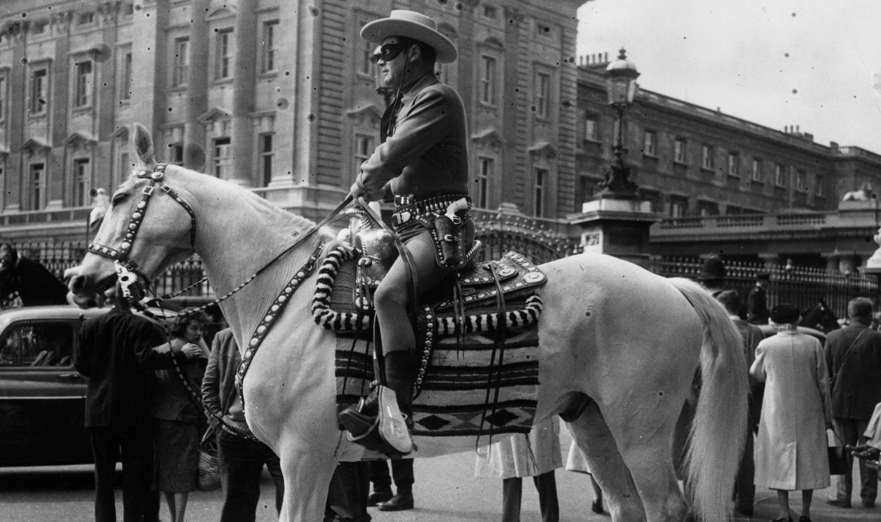The Lone Ranger aka actor Clayton Moore, visits the Horse Guards on parade at Buckingham Palace during his stay in London, where he will appear on Children's Television on BBC and radio programmes.