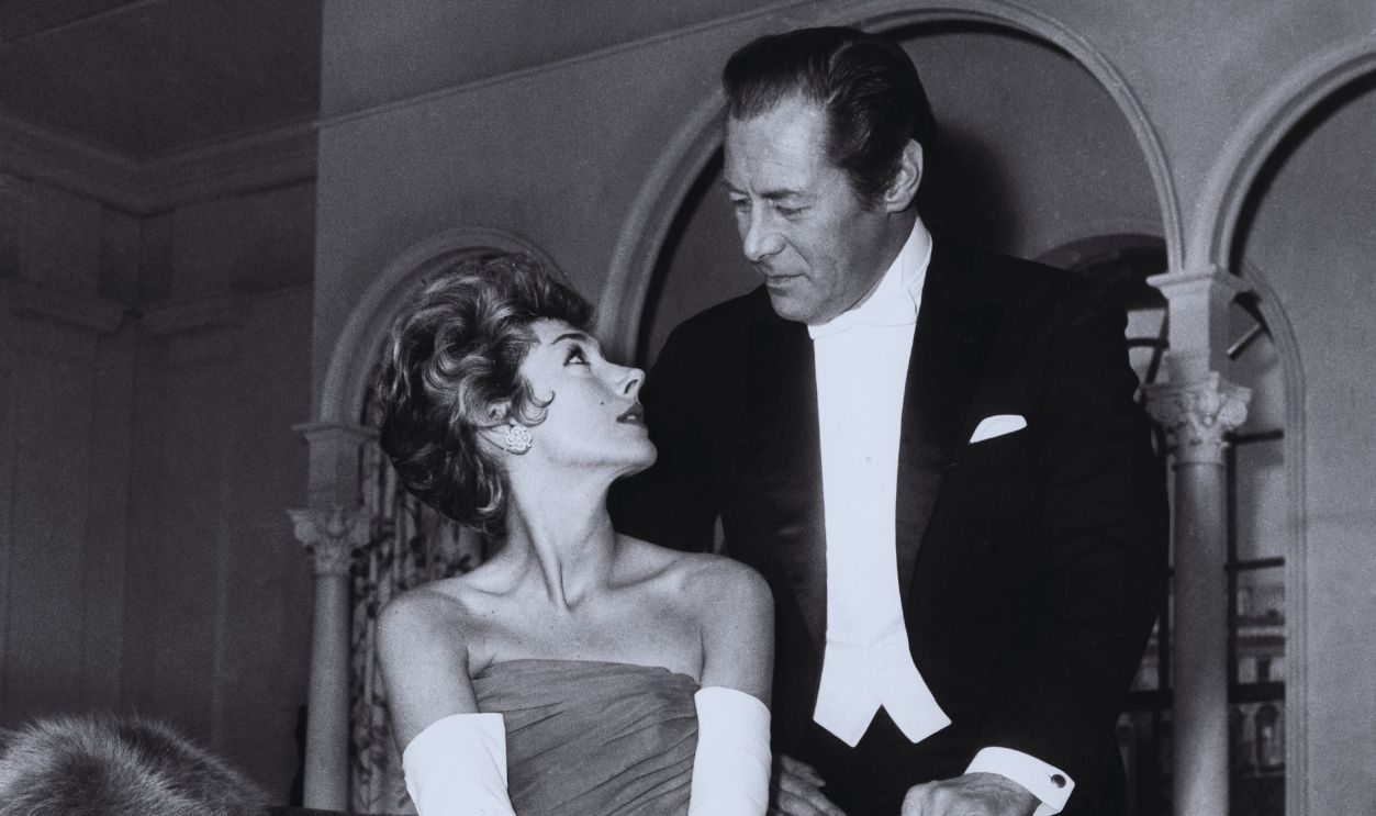 Gettyimages - 842850182, Rex Harrison And Kay Kendall American actor Rex Harrison (1908 - 1990) with his real-life wife, actress Kay Kendall (1927 - 1959), in a scene from the film 'The Reluctant Debutante', being filmed in Paris, France, 10th February 1958. Kendall is wearing a dress by Balmain.