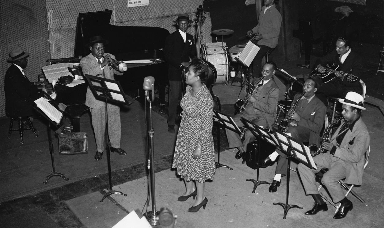 Billie Holiday in the studio at a recording session in New York, L-R Sonny White - piano, Roy Eldridge - trumpet, John Williams - bass, Billie Holiday, Hal West - drums, Jimmy Powell, Carl Frye - alto sax, Kermit Scott - tenor sax, Larry Lucie - guitar, 29th February 1940. 