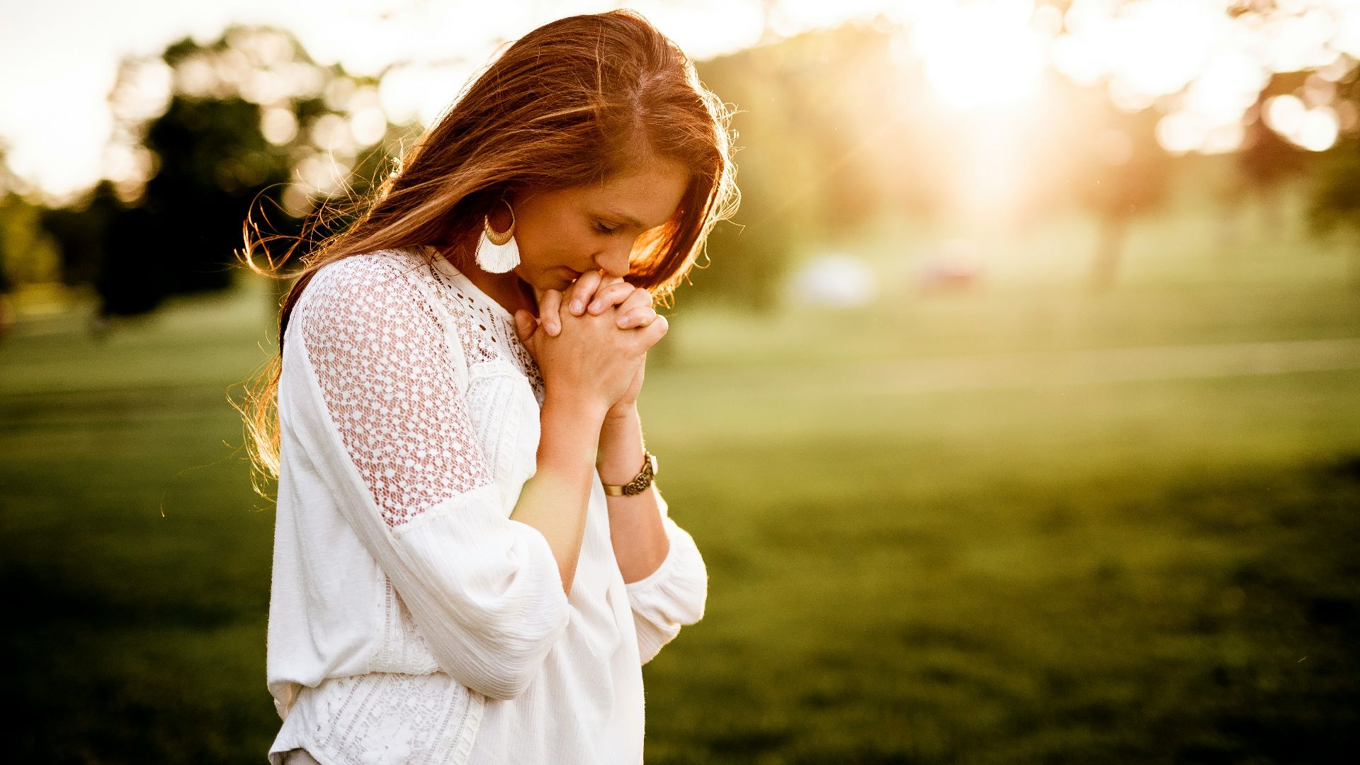 woman praying beside tree