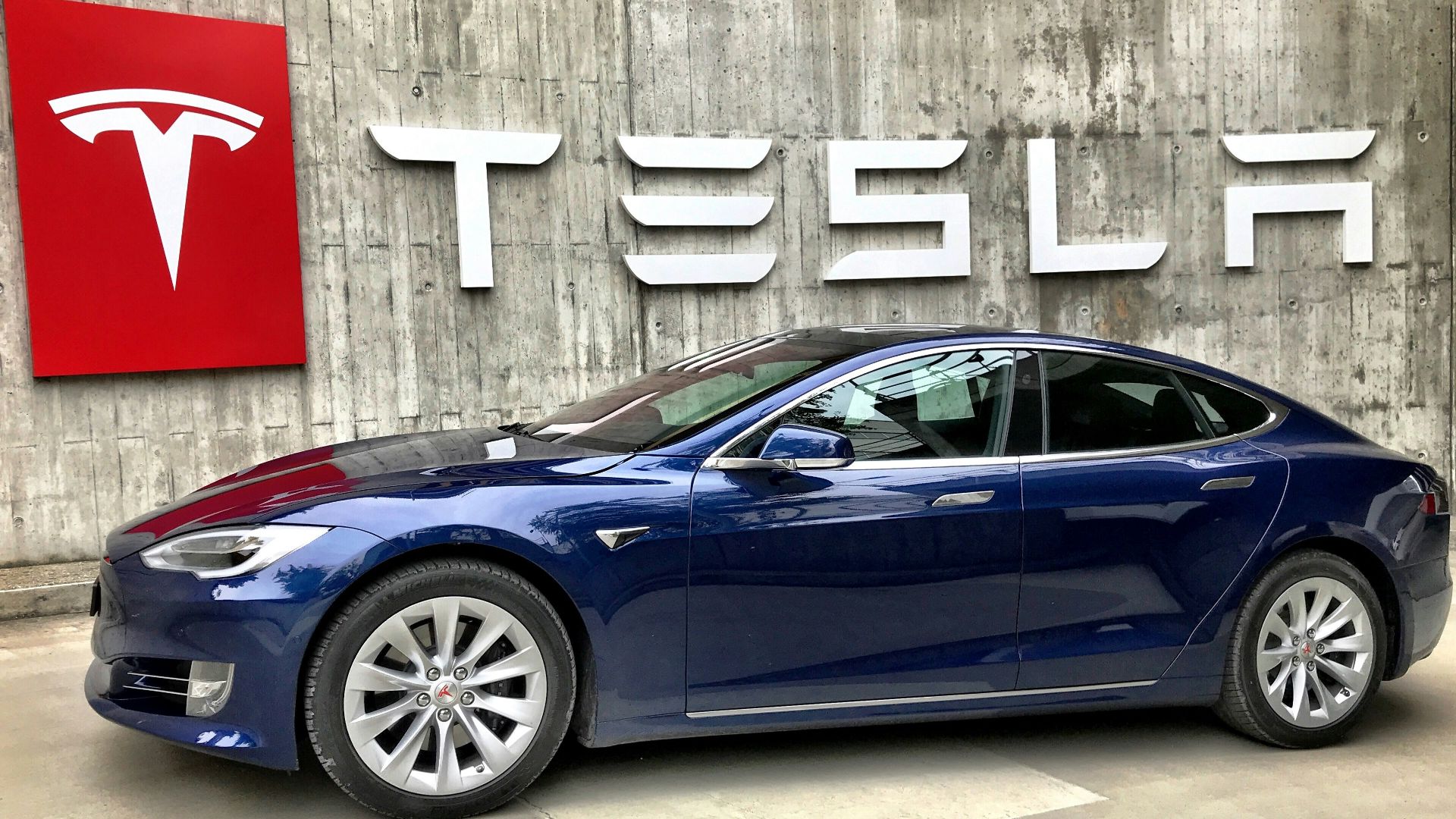 blue coupe parked beside white wall