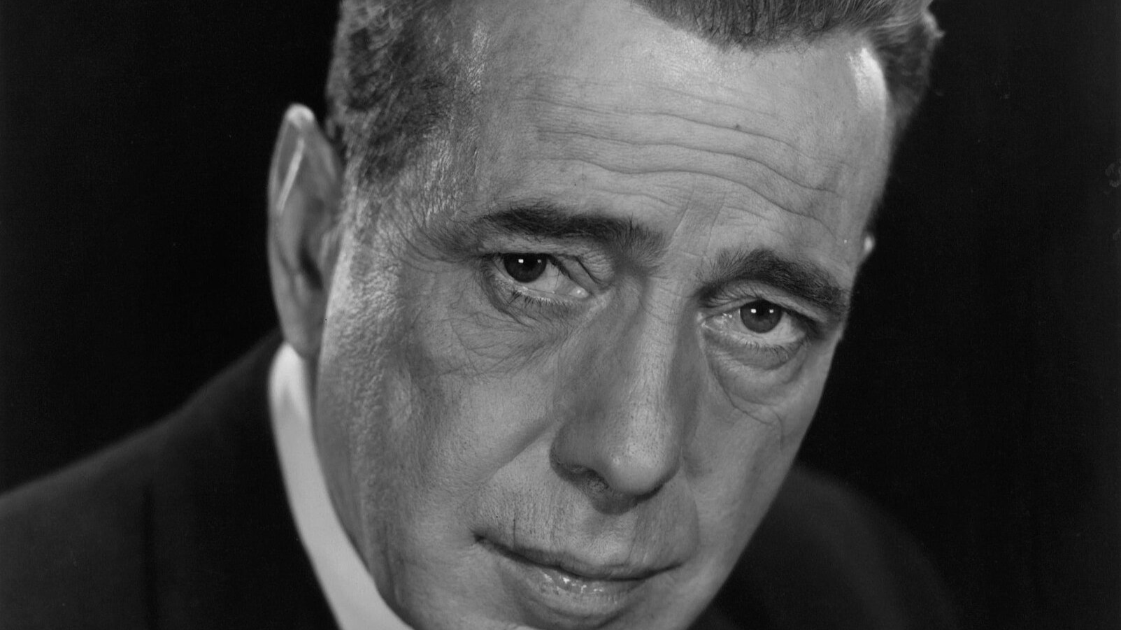 Grayscale Portrait Photo of Humphrey Bogart in a dark suit