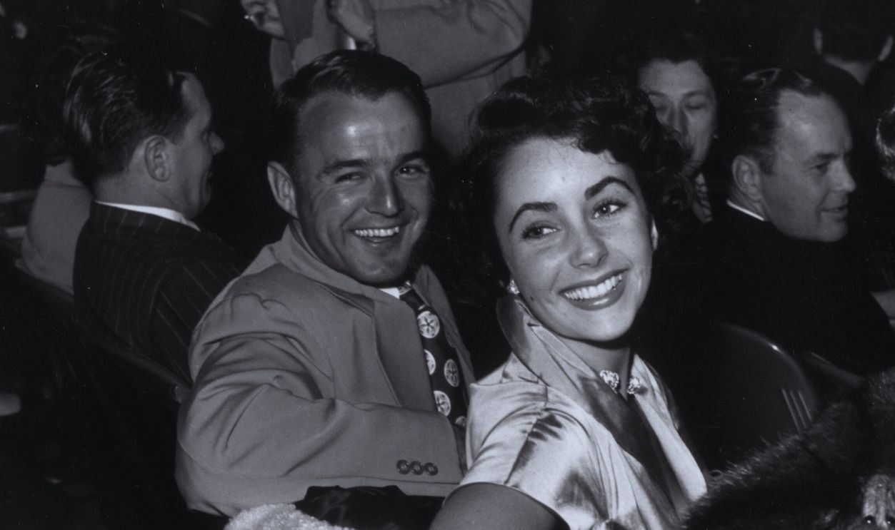 Gettyimages - 3240953, Liz And Guest circa 1945: EXCLUSIVE British-born actress Elizabeth Taylor (centre) turns and smiles as she sits next to football star Glenn Davis at an unidentified movie premiere.